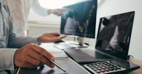 Risico analyse: close-up van 2 mannen welke data en grafieken aan het bekijken zijn op een laptop en beeldscherm